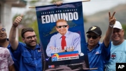 Dos militantes del partido opositor Un Nuevo Tiempo muestran un afiche con la imagen del candidato presidencial Edmundo González Urrutia durante una concentración con el postulado y la dirigente María Corina Machado en Aragua, el 18 de mayo de 2024.