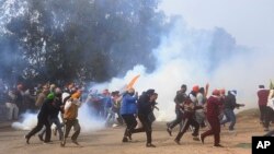 Farmers run for cover after police fired tear gas to disperse protesting farmers who were marching to New Delhi near the Punjab-Haryana border at Shambhu, India, Feb.13, 2024.