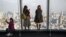 FILE - Visitors take selfies and pictures of the Tokyo skyline from the Roppongi Hills commercial complex, Jan. 20, 2018.