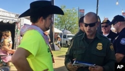 In this April 6, 2017 photo, a U.S. Border Patrol agent gives information about working for the agency to 24-year-old Ric Kindle, of the Phoenix area, at the Country Thunder Music Festival in Florence, Ariz. 