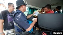 Malaysian police personnel checks identity of passengers on a road leading to Kampung Tanduo, where Malaysian troops stormed the camp of an armed Filipino group, in Lahad Datu, Sabah state, March 8, 2013. 