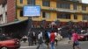 Pedestrians walk past a sign reading "Ebola Disease Outbreak" outside the Ministry of Finance in Monrovia, Liberia, Jan. 12, 2015.