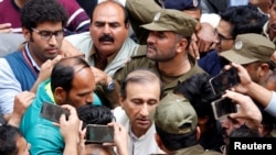 FILE - Police officers and journalists surround Mir Shakil-ur-Rahman, the owner and editor-in-chief of Geo television news channel and the Jang group of newspapers, as he leaves after court proceedings in Lahore, Pakistan, March 13, 2020.
