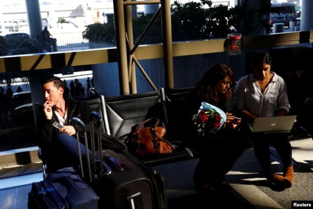 A passenger, left, waits in Los Angeles International Airport for his girlfriend, who was born in Iran but holds a Canadian passport and had not been allowed entry to the U.S. after vacationing in Thailand. Meanwhile, an attorney works to help family members of Sarah Saedian, center right, also affected by a presidential executive order on immigration, Jan. 28, 2017.