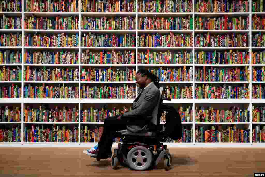 British-born Nigerian artist Yinka Shonibare poses with his art piece, called "The British Library," at Tate Modern in London, April 8, 2019.