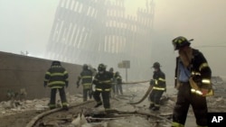 FILE - With the skeleton of the World Trade Center twin towers in the background, New York City firefighters work amid debris on Cortlandt Street after the terrorist attacks of Sept. 11, 2001.
