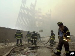 FILE - With the skeleton of the World Trade Center twin towers in the background, New York City firefighters work amid debris on Cortlandt Street after the terrorist attacks of Sept. 11, 2001.