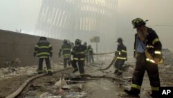 FILE - With the skeleton of the World Trade Center twin towers in the background, New York City firefighters work amid debris on Cortlandt Street after the terrorist attacks of Sept. 11, 2001.