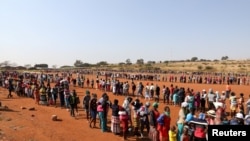 People stand in a queue to receive food aid, during the COVID outbreak at the Itireleng informal settlement, near Laudium suburb in Pretoria, South Africa, May 20, 2020. 