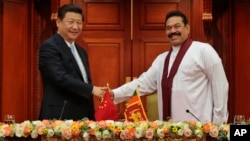 ປະທານາທິບໍດີ ສຣີ ລັງກາ ທ່ານ Mahinda Rajapaksa, ຂວາ, ຈັບມືກັບ ປະທານປະເທດຈີນ ທ່ານ Xi Jinping ໃນລະຫວ່າງການພົບປະກັນ ຢູ່ ໂຄລົມໂບ.