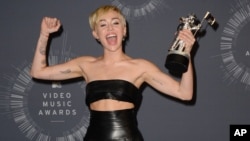 FILE - Miley Cyrus poses with the Video of the Year award in the press room at the MTV Video Music Awards in Inglewood, California, Aug. 24, 2014.