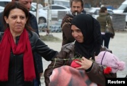 FILE - An activist gives a red carnation to a Syrian refugee woman to promote an International Women’s Day rally to be held March 8, in Diyarbakir, Turkey March 1, 2018.