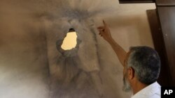 A Palestinian man points at a damaged ceiling of a house following an Israeli airstrike in Nuseirat refugee camp, June 3, 2012. 