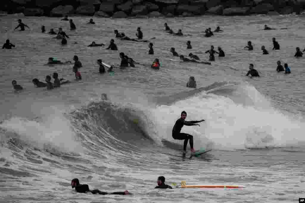 People surf on a beach reopened for sport activities after the coronavirus lockdown in Barcelona, Spain, May 9, 2020.