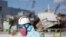 FILE - A Tokyo Electric Power Co. (TEPCO) employee, wearing a protective suit and a mask, walks in front of the No. 1 reactor building at the tsunami-crippled Fukushima Dai-ichi nuclear power plant in Okuma, Fukushima Prefecture, northeastern Japan, Wedne
