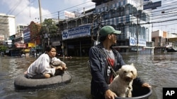 A Thai resident uses a makeshift float to keep his dog dry as he pulls a woman along flooded streets in Rangsit district at the outskirts of Bangkok, Thailand, October 21, 2011.