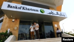 FILE - Customers wait outside a branch of the Bank of Khartoum, in Khartoum, Sudan, Sept. 11, 2017. 