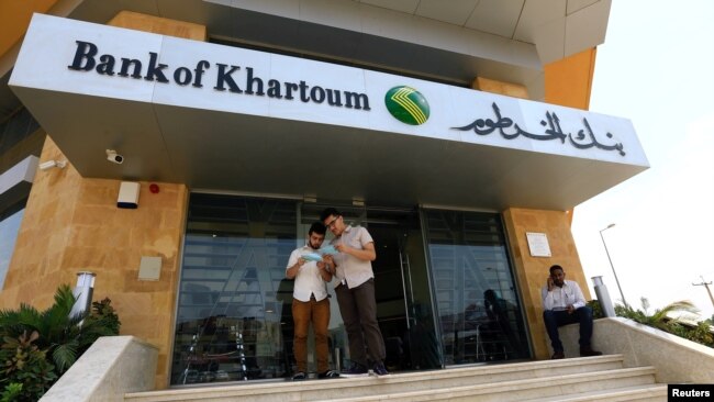 FILE - Customers wait outside a branch of the Bank of Khartoum, in Khartoum, Sudan, Sept. 11, 2017. 