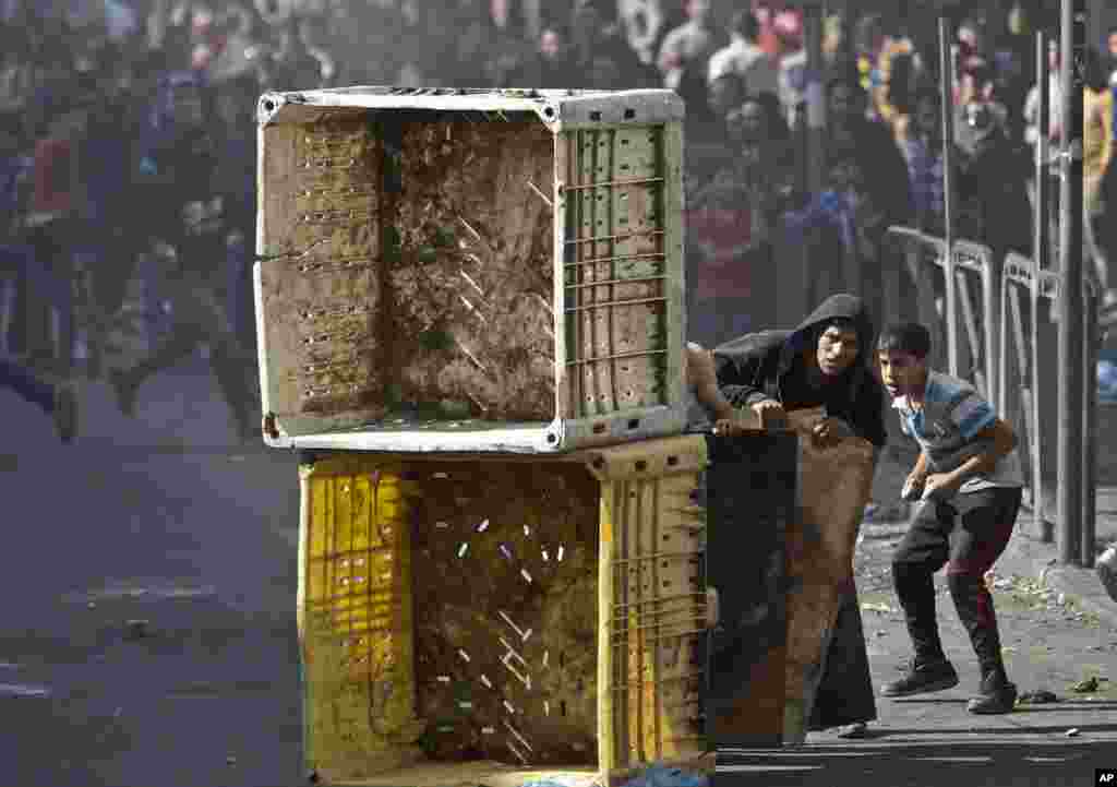 Palestinians take cover during clashes with Israeli soldiers following a rally marking the 9th anniversary of late Palestinian leader Yasser Arafat&#39;s death, in the West Bank city of Hebron. 