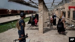 Los civiles iraquíes huyen a través de una estación de tren dañada durante las luchas entre las fuerzas de seguridad iraquíes y los militantes del Estado islámico, en el lado occidental de Mosul, Irak, el domingo 19 de marzo de 2017.