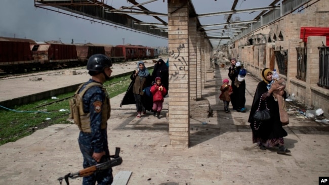 Los civiles iraquíes huyen a través de una estación de tren dañada durante las luchas entre las fuerzas de seguridad iraquíes y los militantes del Estado islámico, en el lado occidental de Mosul, Irak, el domingo 19 de marzo de 2017.