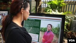 A woman reads a biography of LGBTIQ community members, displayed at a photo exhibition during a report launch at the Cambodian Center for Human Rights, Phnom Penh, on Dec. 9, 2019. (Kann Vicheika/VOA Khmer) 