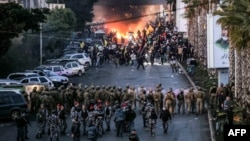 Tires burn as supporters of Lebanese Shiite Islamist movement Hezbollah stand before Lebanese Army soldiers during a Hezbollah-organized rally to block the road to Beirut International Airport over a decision to bar two Iranian flights from landing there, Feb. 15, 2025.