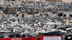 FILE - A worker sets banners at the port warehouses that were destroyed by Aug. 4 explosion that hit the seaport of Beirut, Lebanon, Aug. 19, 2020. 