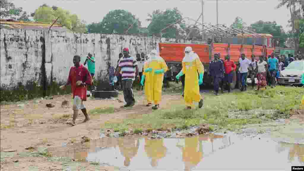 Health workers surround an Ebola patient who escaped from the Elwa Hospital, Paynesville, Liberia, Sept. 1, 2014 .
