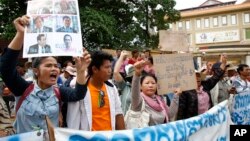 A supporter (L) holds up portraits of opposition lawmakers of the Cambodia National Rescue Party (CNRP) who were charged with leading an insurrection movement during a rally in front of Phnom Penh Municipality Court in Phnom Penh, Cambodia, July 17, 2014.