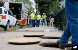 A worker with Columbia gas stands over an open man hole as the crew works to make sure there are no gas leaks at the corner of Parker and Salem Streets in Lawrence, Mass., Sept. 14, 2018.