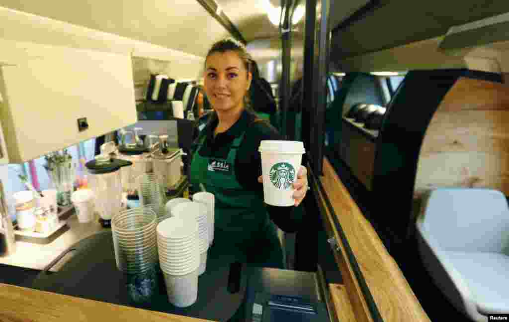 An employee of Starbucks holds a cup of coffee at a new Starbucks store on a train of Swiss rail operator SBB in Zurich. The world&#39;s largest coffee chain Starbucks presented its first double-deck store on a SBB Intercity train travelling between the Swiss cities of St. Gallen and Geneva, Nov. 14, 2013.