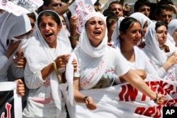 FILE - Yazidi Kurdish women chant slogans during a protest against the Islamic State group's invasion of Sinjar city a year earlier, in Dohuk, northern Iraq, Aug. 3, 2015.