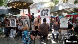 Para pelukis jalanan sedang membuat sketsa potret di “Place du Tertre”, alun-alun di kawasan Butte Montmartre di Paris, Perancis, 2 Agustus 2018.