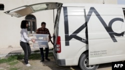 Members of the Kurdistan Centre for Arts and Culture, carry a box of old books to a van to be taken for scanning, as part of an effort to digitise historic Kurdish volumes and manuscripts, in the northern Iraqi city of Dohuk on Feb. 13, 2024.