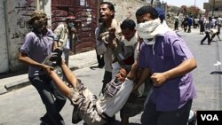 Manifestantes cargan un herido durante choques con la policía en la ciudad de Taiz.