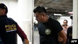 Members of the General Inspectorate of the Guatemalan National Civil Police guard an arrested police member on arrival at a court hearing, in Guatemala City on Oct. 1, 2024, following the dismantling of a human trafficking network.