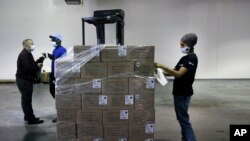 Dr. Abhu Kaur of Khalsa Aid USA, a global humanitarian organization, labels a pallet of electrical transformers, which will be shipped to New Delhi with oxygen concentrators this week, on New York’s Long Island, Friday, May 7, 2021. (AP Photo/Jessie Warda