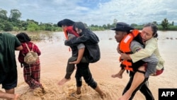 Police carry residents through floodwaters in Pyinmana town, located in Myanmar's Naypyidaw region, following heavy rains in the aftermath of Typhoon Yagi.