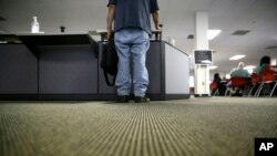 FILE - A lone job seeker checks in at the front desk of the Texas Workforce Solutions office in Dallas, March 10, 2017.