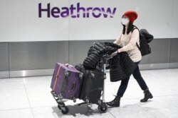 Passengers wear face masks as the push their luggage after arriving from a flight at Terminal 5 of London Heathrow Airport in west London, Jan. 28, 2020.