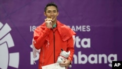 Jonatan Christie berpose memegang medali emas.