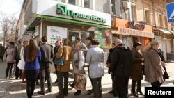 FILE - People are seen lining up to withdraw money at an ATM at a Privatbank branch in Simferopol, Crimea, March 14, 2014.