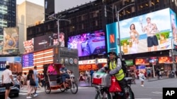 Sergio Solano, un inmigrante de México, pasea en bicicleta por Times Square mientras realiza una entrega, el 21 de junio de 2024, en Nueva York.