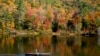 A fly fisherman paddles on a pond as fall foliage begins to show color in Campton, N.H., Oct. 6, 2024.