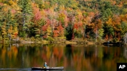 A fly fisherman paddles on a pond as fall foliage begins to show color in Campton, N.H., Oct. 6, 2024.