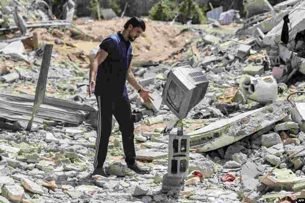 Palestinian performance artist Mohammed al-Shenbari stacks up a television atop a bottle as he demonstrates his skills in balancing objects, in the ruins of houses destroyed by Israeli air strikes the May 2021 conflict between Israel and Hamas, in Beit Lahia in the northern Gaza Strip, July 6, 2021.&nbsp;