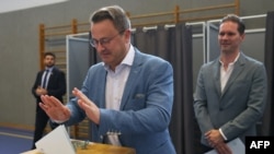 Luxembourg's Prime Minister Xavier Bettel, center, casts his ballot while his husband, Gauthier Destenay, right, watches at a polling station as part of the vote for legislative elections in Luxembourg, on Oct. 8, 2023.