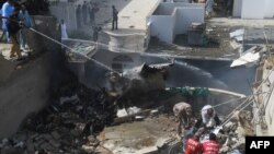 Petugas berupaya memadamkan api kebakaran dari pesawat milik maskapai Pakistan International Airlines (PIA) yang jatuh di kawasan permukiman di Karachi, Pakistan, 22 Mei 2020.