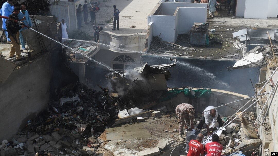 Petugas berupaya memadamkan api kebakaran dari pesawat milik maskapai Pakistan International Airlines (PIA) yang jatuh di kawasan permukiman di Karachi, Pakistan, 22 Mei 2020.